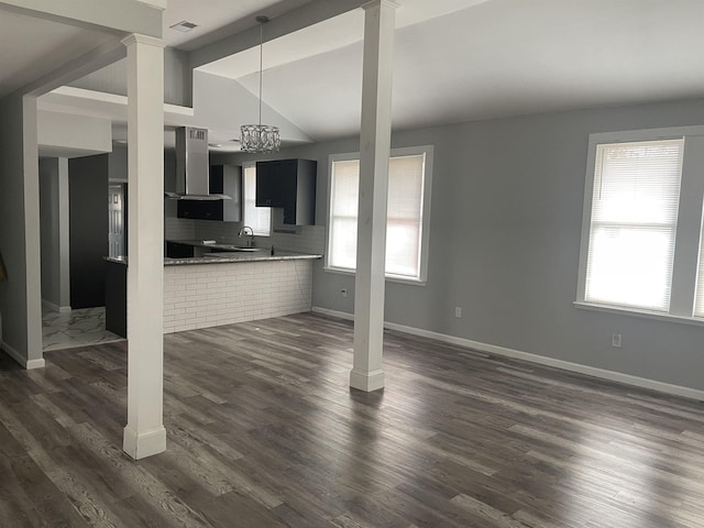 unfurnished living room featuring ornate columns, vaulted ceiling, and dark hardwood / wood-style flooring