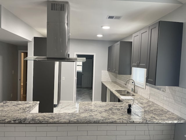 kitchen with sink, gray cabinetry, light stone counters, tasteful backsplash, and island exhaust hood