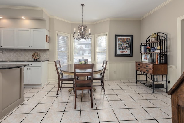 dining space with crown molding, a notable chandelier, and light tile patterned floors