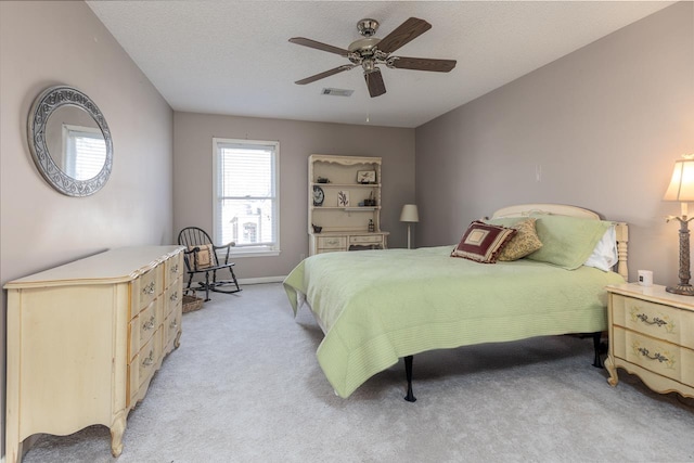 carpeted bedroom featuring ceiling fan and a textured ceiling