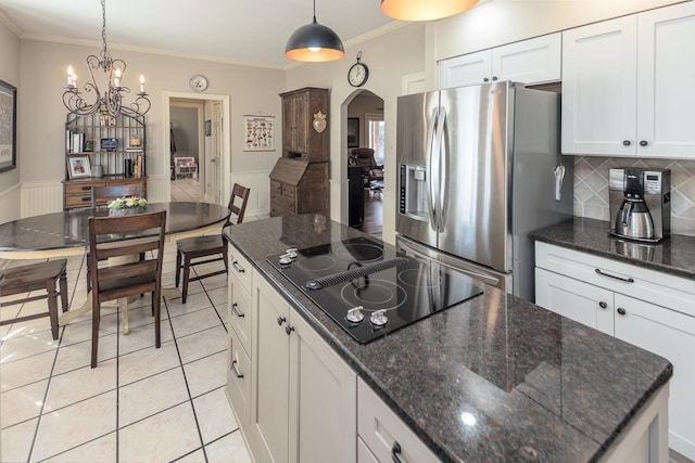 kitchen with hanging light fixtures, stainless steel refrigerator with ice dispenser, black electric stovetop, and white cabinetry