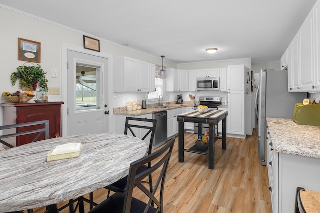 kitchen with stainless steel appliances, white cabinetry, and light stone counters