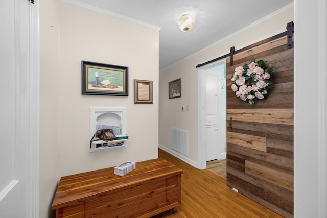 hallway featuring ornamental molding, a barn door, and light hardwood / wood-style flooring