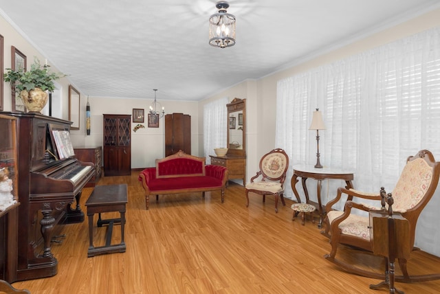 sitting room featuring ornamental molding, a notable chandelier, and light wood-type flooring