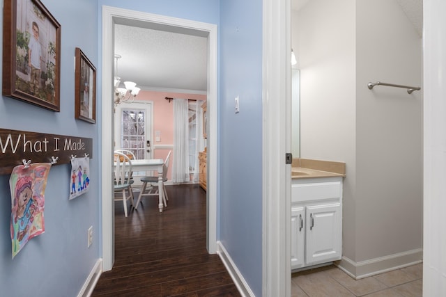 hallway featuring hardwood / wood-style floors, a notable chandelier, and a textured ceiling