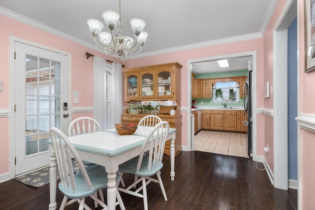 dining area with ornamental molding, sink, an inviting chandelier, and light hardwood / wood-style floors