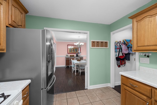 kitchen with light tile patterned flooring, decorative light fixtures, stove, a notable chandelier, and stainless steel fridge with ice dispenser