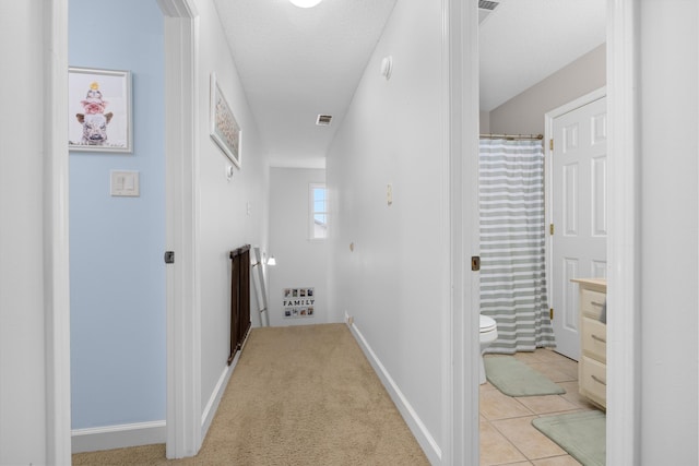 hallway featuring a textured ceiling and light tile patterned floors