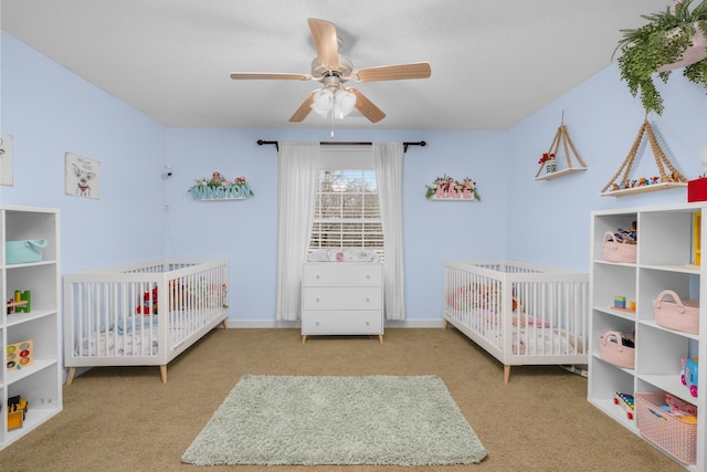 carpeted bedroom featuring a textured ceiling, a crib, and ceiling fan