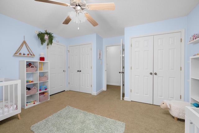 bedroom featuring two closets, light colored carpet, and ceiling fan