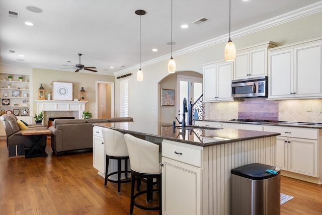 kitchen with sink, dark stone countertops, stainless steel appliances, a fireplace, and an island with sink