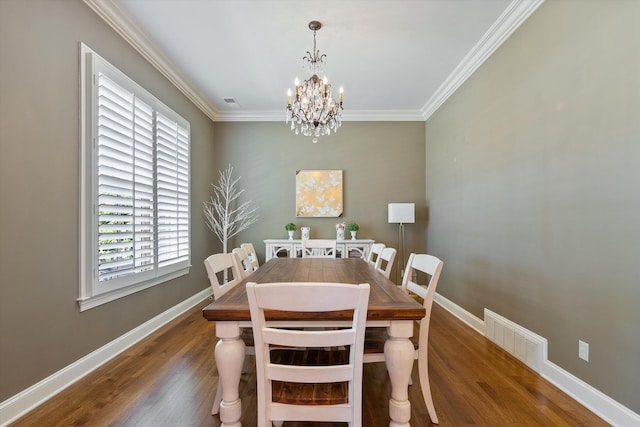 dining area with dark wood-type flooring, crown molding, and a notable chandelier