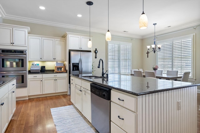 kitchen featuring pendant lighting, crown molding, appliances with stainless steel finishes, a kitchen island with sink, and light wood-type flooring