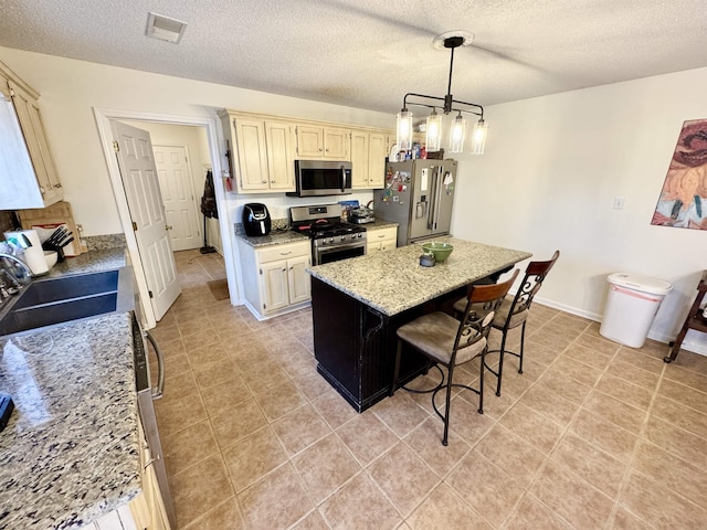 kitchen featuring a kitchen island, a breakfast bar, hanging light fixtures, stainless steel appliances, and light stone countertops