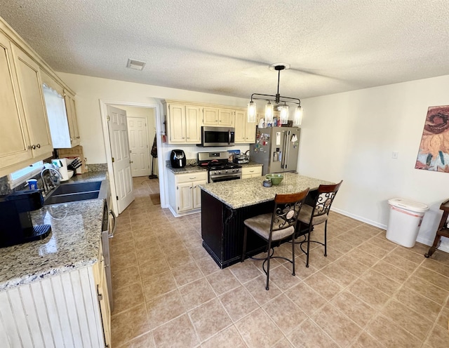 kitchen with decorative light fixtures, a kitchen breakfast bar, a center island, stainless steel appliances, and light stone countertops