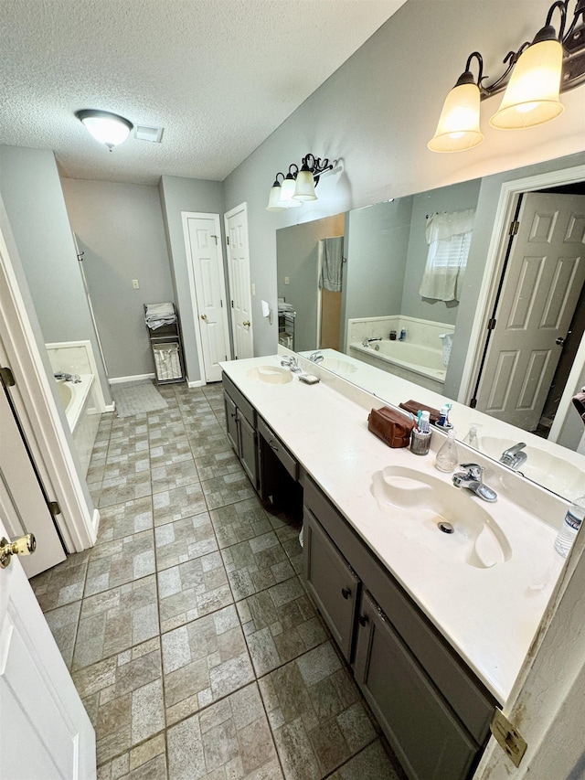 bathroom featuring vanity, a textured ceiling, and a bathing tub