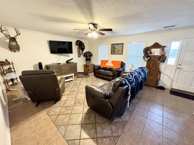 tiled living room featuring ceiling fan, ornamental molding, and a textured ceiling