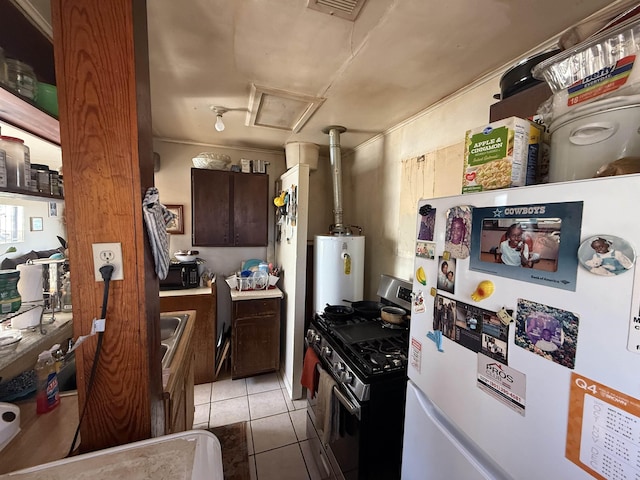 kitchen featuring light tile patterned floors, sink, water heater, white refrigerator, and stainless steel gas range oven