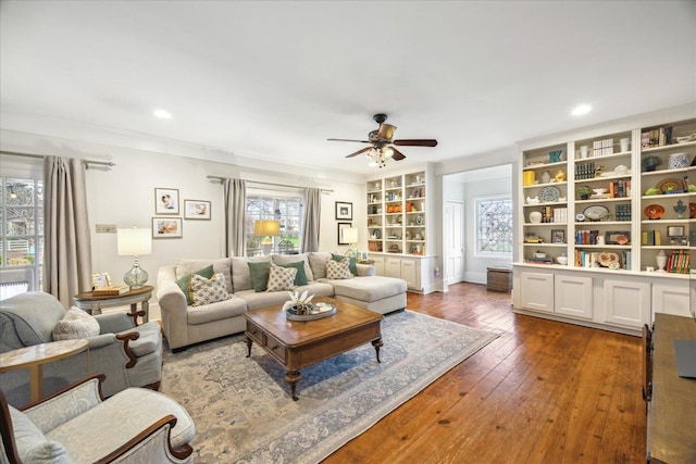 living room with dark wood-type flooring, built in features, and ceiling fan