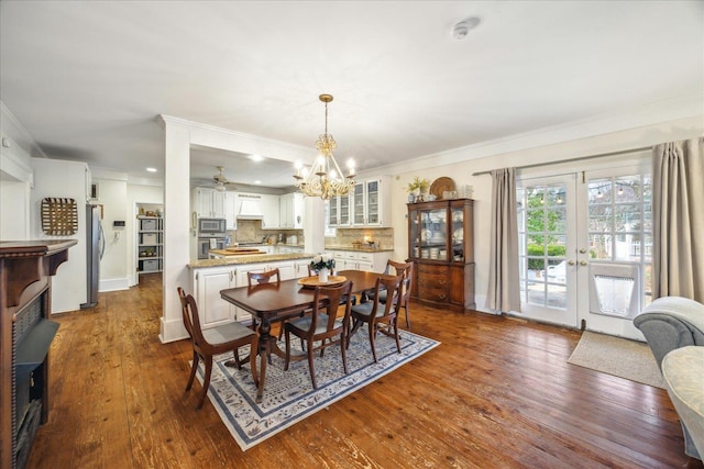 dining space with dark wood-type flooring, ornamental molding, french doors, and a chandelier