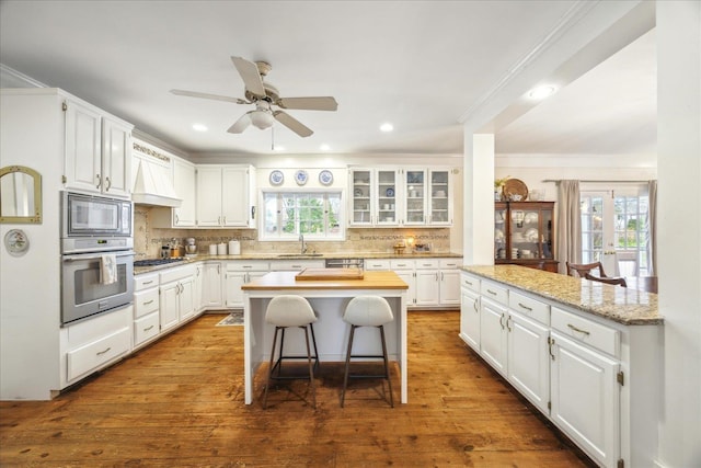 kitchen with appliances with stainless steel finishes, a kitchen breakfast bar, a kitchen island, and white cabinets