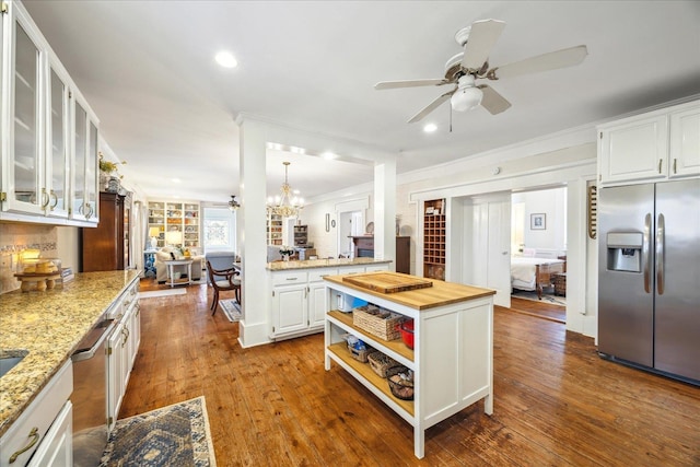 kitchen featuring hardwood / wood-style flooring, appliances with stainless steel finishes, white cabinetry, wood counters, and decorative light fixtures