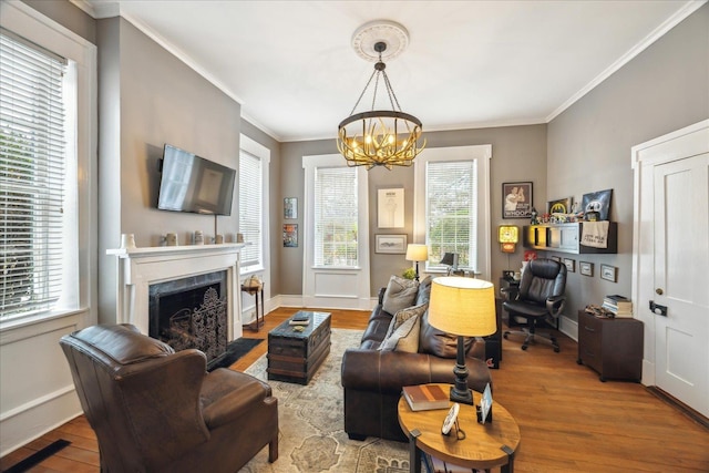 living room with ornamental molding, a fireplace, a chandelier, and light wood-type flooring