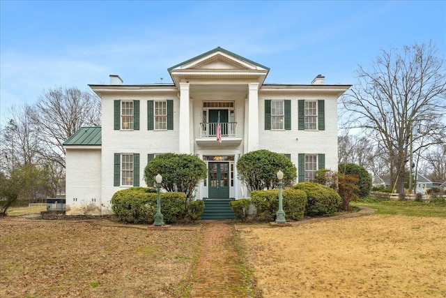 greek revival house featuring a front lawn and a balcony