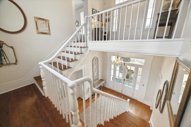 staircase featuring a high ceiling, hardwood / wood-style floors, and a notable chandelier