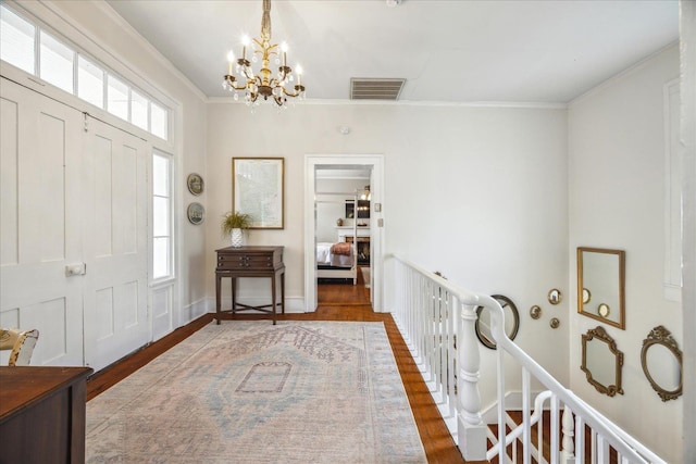 entryway with an inviting chandelier, ornamental molding, and dark hardwood / wood-style floors