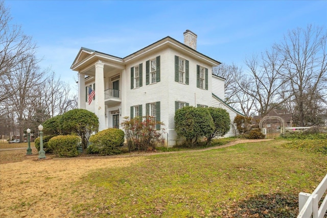 view of home's exterior with a balcony and a lawn