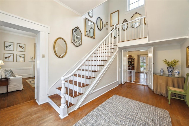 stairs with crown molding, a wealth of natural light, and wood-type flooring