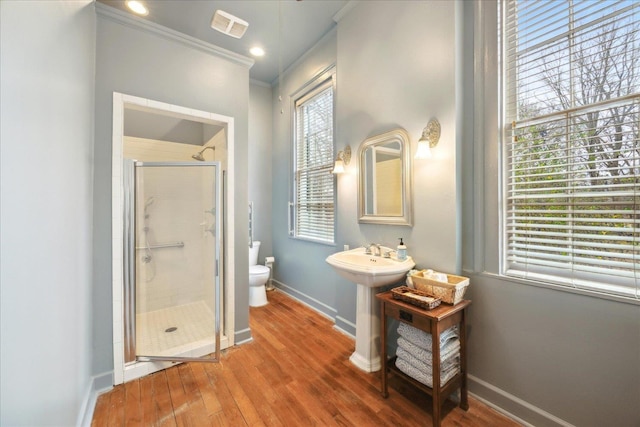 bathroom featuring ornamental molding, toilet, a shower with door, and hardwood / wood-style floors