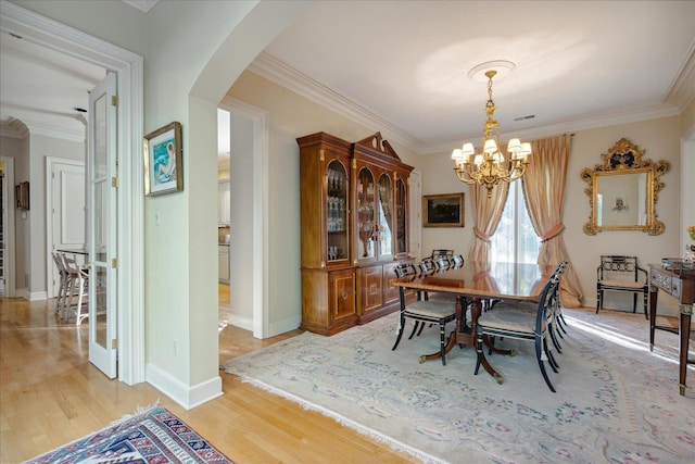 dining area featuring light hardwood / wood-style flooring, ornamental molding, and a chandelier