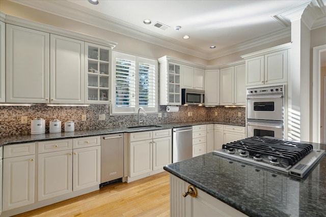 kitchen featuring sink, backsplash, stainless steel appliances, and dark stone counters