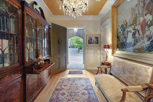 foyer entrance with crown molding, light hardwood / wood-style floors, and a chandelier