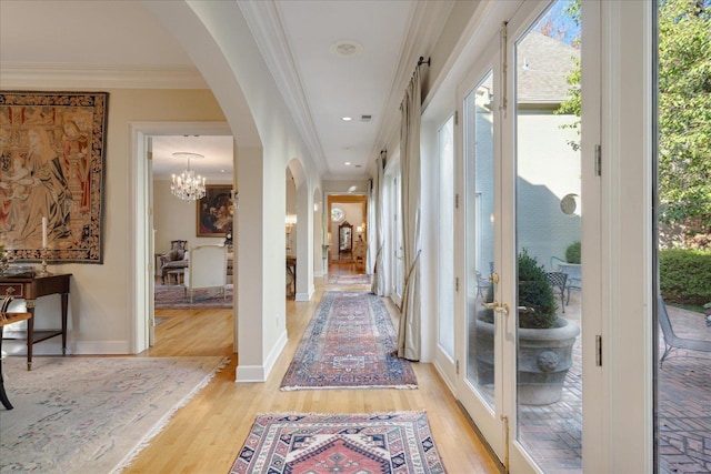 hallway featuring crown molding, an inviting chandelier, and light wood-type flooring