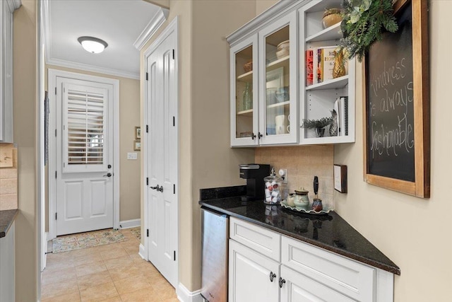 bar featuring light tile patterned flooring, dark stone countertops, white cabinets, decorative backsplash, and ornamental molding