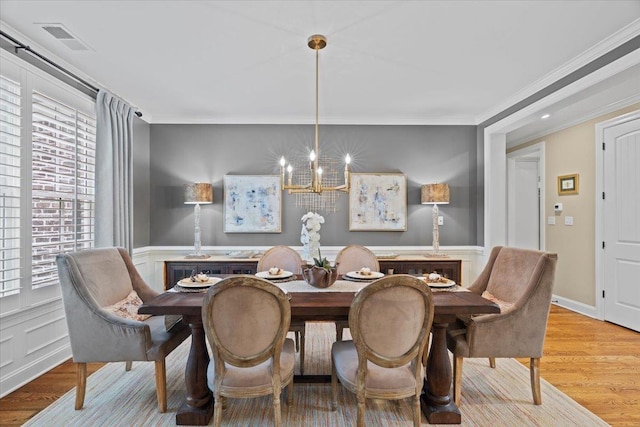 dining room featuring an inviting chandelier, crown molding, and light hardwood / wood-style flooring