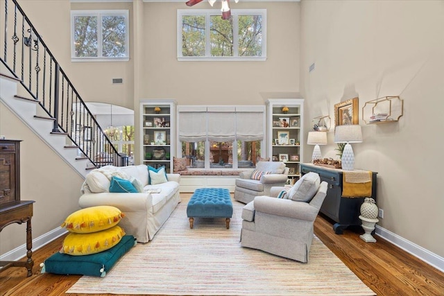 living room featuring ceiling fan, plenty of natural light, hardwood / wood-style floors, and a high ceiling