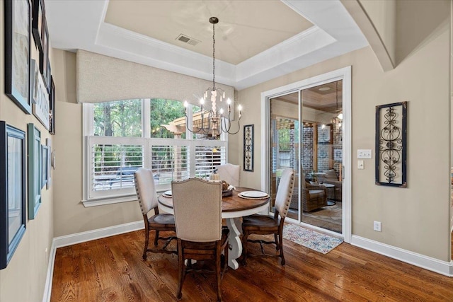 dining space with an inviting chandelier, hardwood / wood-style floors, a tray ceiling, and crown molding