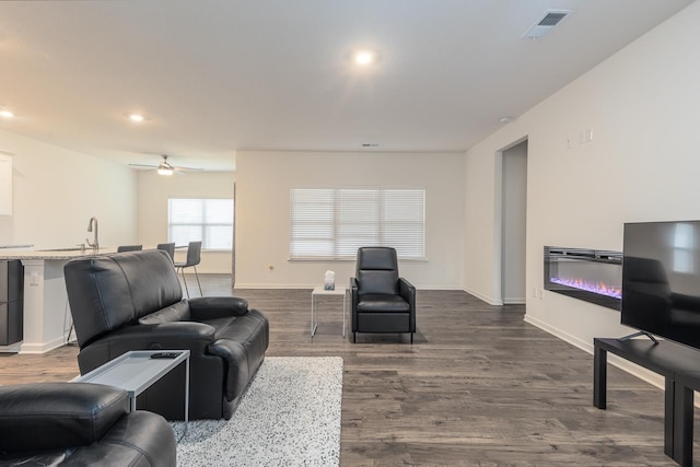 living room featuring ceiling fan, sink, and hardwood / wood-style floors