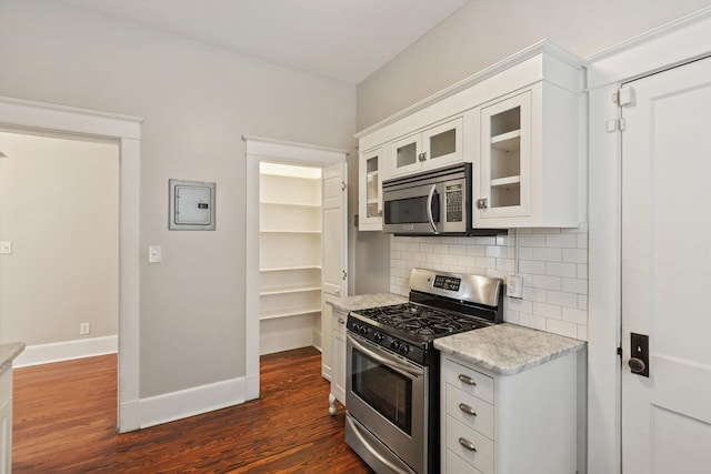 kitchen with appliances with stainless steel finishes, white cabinets, and backsplash