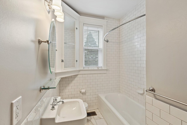 bathroom featuring tiled shower / bath, sink, and tile walls