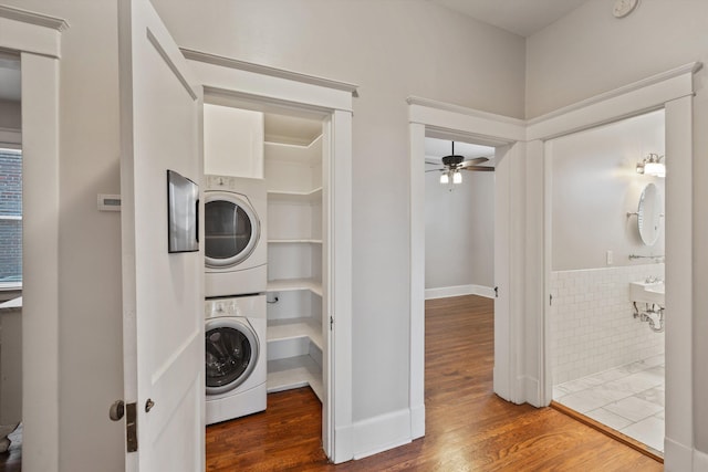 laundry room with dark wood-type flooring, ceiling fan, and stacked washer / dryer