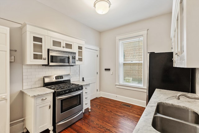 kitchen featuring sink, backsplash, white cabinets, light stone counters, and stainless steel appliances