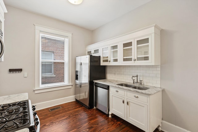 kitchen featuring sink, appliances with stainless steel finishes, backsplash, light stone counters, and white cabinets