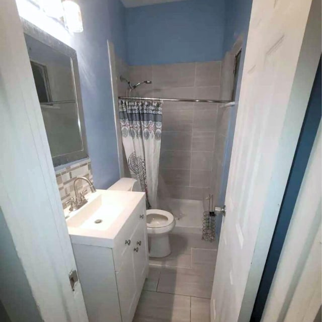 bathroom with tile patterned flooring, backsplash, vanity, curtained shower, and toilet