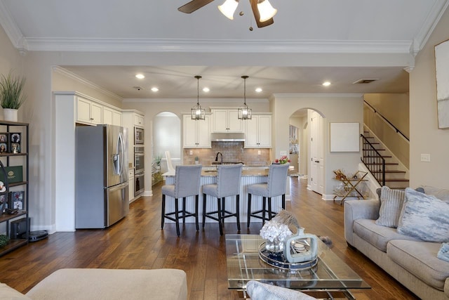 living room featuring dark hardwood / wood-style flooring, sink, ornamental molding, and ceiling fan