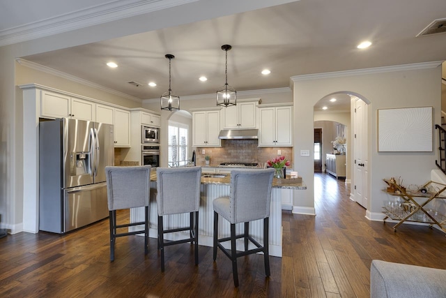 kitchen with stainless steel appliances, hanging light fixtures, a center island with sink, and white cabinets